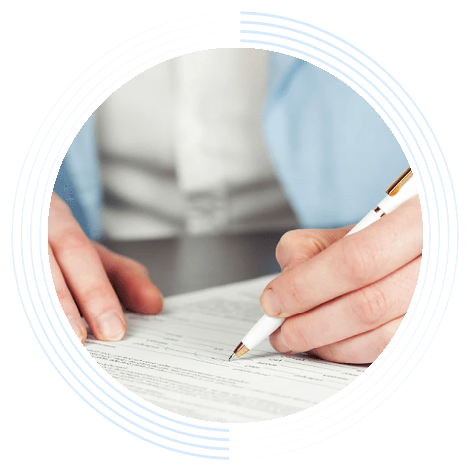 Hands hold a pen writing on a document, surrounded by a patterned circular design, with a blurred blue-sleeved figure in the background.